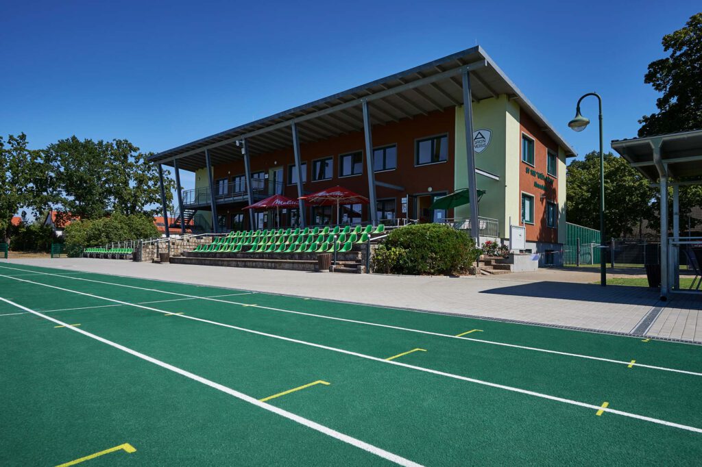 Tribüne und Kunstrasenfeld der Sportanlage des SV 1908 Grün-Weiss Ahrensfelde bei Sonnenschein