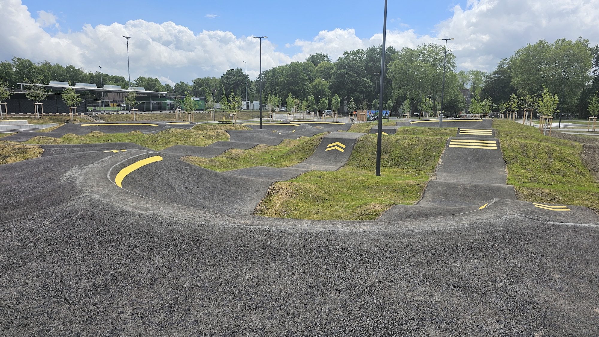 Gesamtansicht des Pumptracks Bochum in der Sportanlage Grüne Dickebank mit Wellenbahnen, Kurven und barrierefreier Gestaltung.